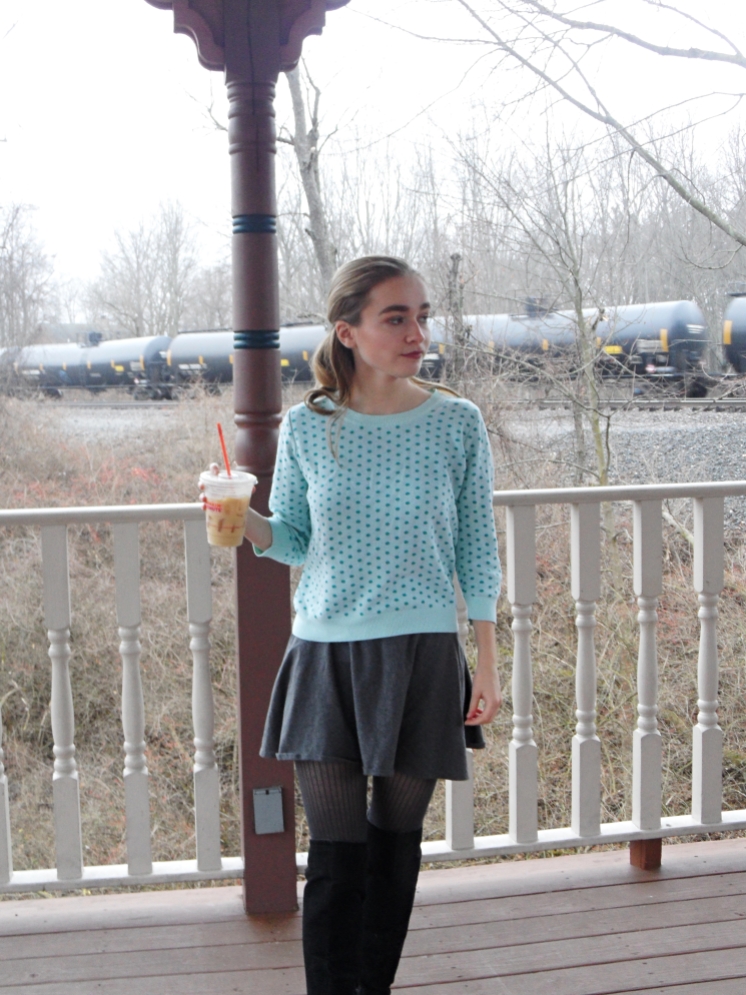 fashion blogger wears polka dot sweater and drinks coffee